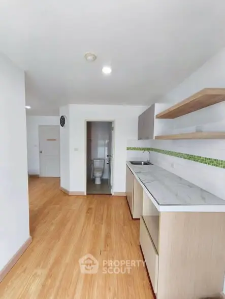 Modern kitchen with open layout and wooden flooring in a bright apartment