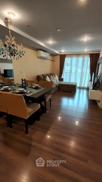 Spacious living room with elegant chandelier and modern decor in a luxurious apartment.