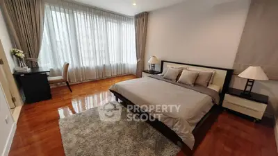 Spacious bedroom with elegant decor and large windows offering natural light.