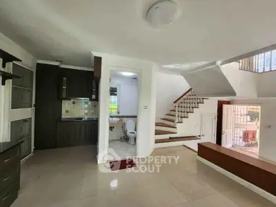 Spacious open-plan living area with staircase and modern kitchen in a bright home interior.