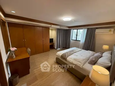 Spacious bedroom with wooden flooring and modern decor in a high-rise apartment.