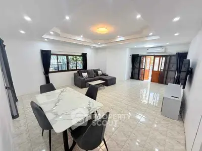 Spacious modern living room with elegant marble dining table and cozy seating area.