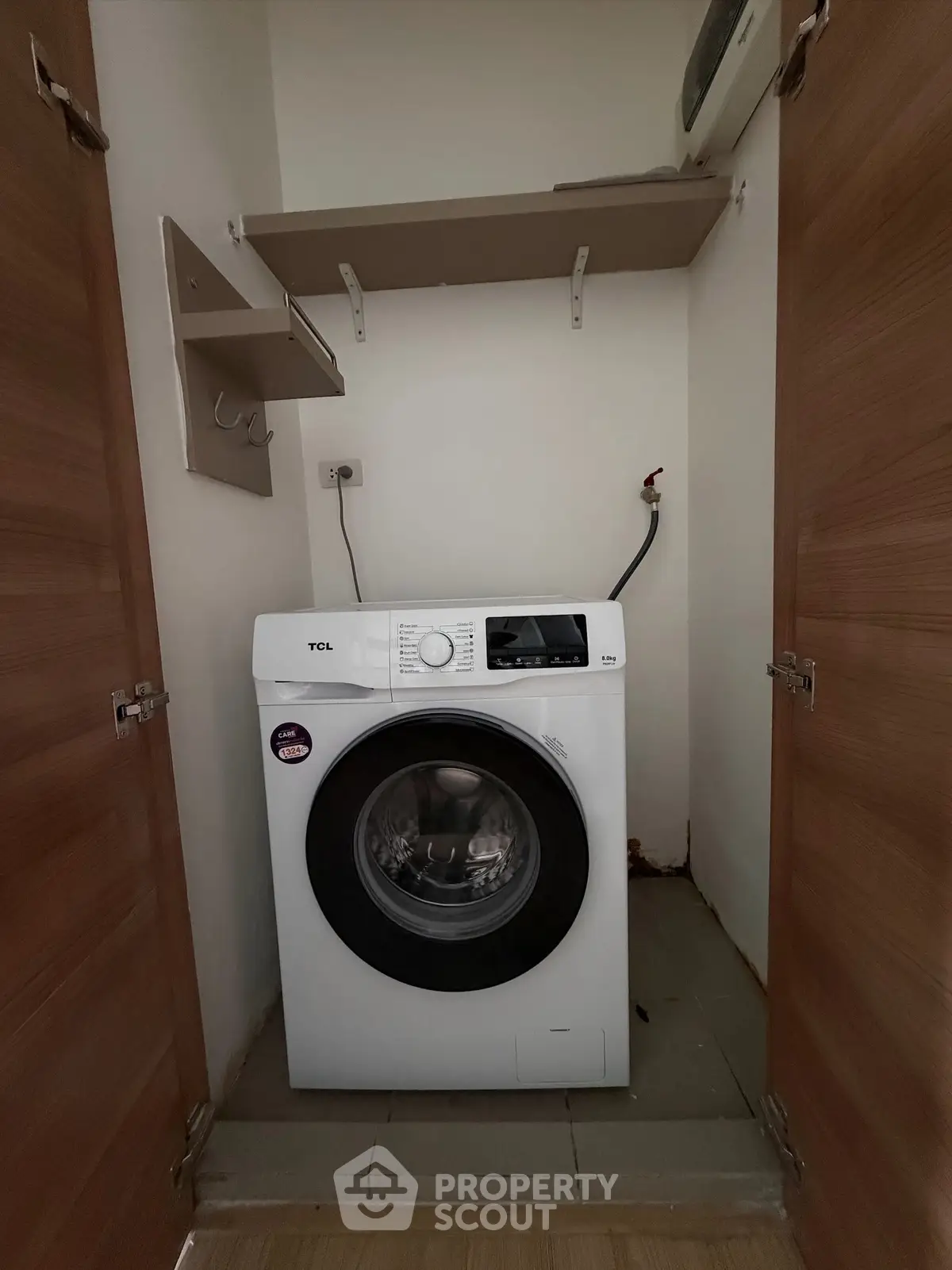 Compact laundry space with modern washing machine and storage shelves.