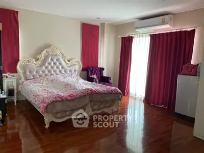 Luxurious bedroom with elegant bed and rich red curtains, featuring polished wooden floors and air conditioning.
