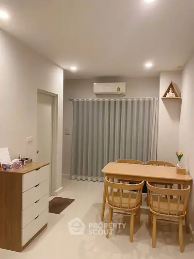 Cozy dining area with wooden table and chairs, air conditioning, and modern decor in a bright apartment.