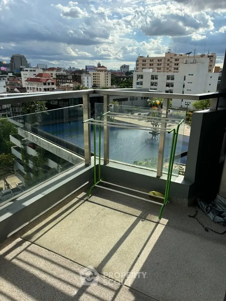 Stunning rooftop view with glass railing overlooking cityscape and pool, perfect for relaxation.
