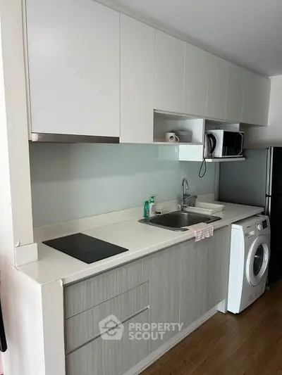 Modern kitchen with sleek cabinetry, washing machine, and built-in appliances in a compact layout.