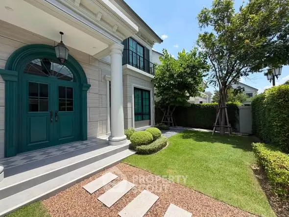 Elegant two-story house with lush garden and classic entrance