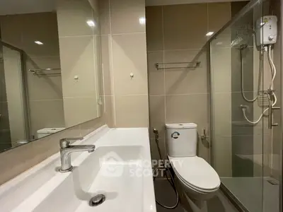 Modern bathroom with sleek fixtures and glass shower enclosure in contemporary apartment.