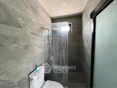 Modern bathroom with sleek gray tiles and glass shower enclosure
