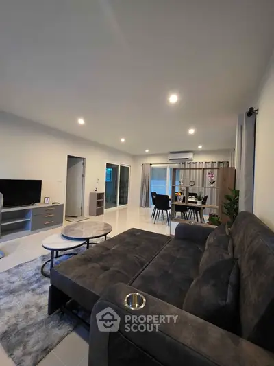 Spacious modern living room with plush sofa and dining area, perfect for family gatherings.