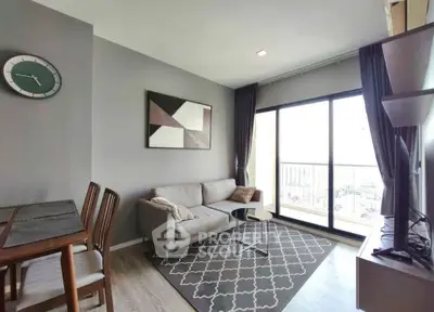 Modern living room with stylish decor and large window offering natural light and city view.