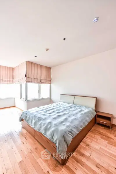 Spacious bedroom with natural light and wooden flooring