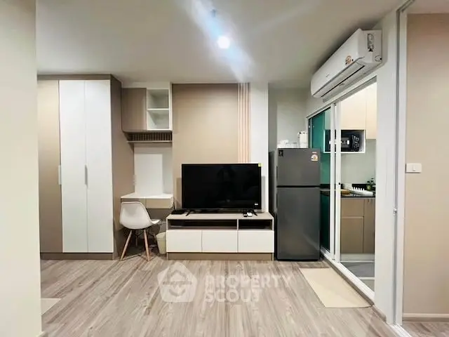 Modern living room with sleek design, featuring TV, storage, and adjacent kitchen area.