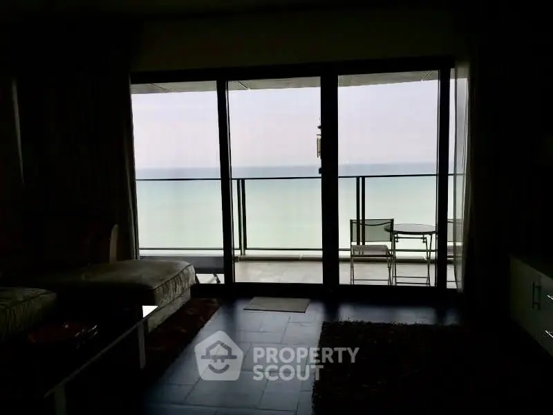 Luxurious living room with stunning ocean view from floor-to-ceiling windows and elegant balcony seating.