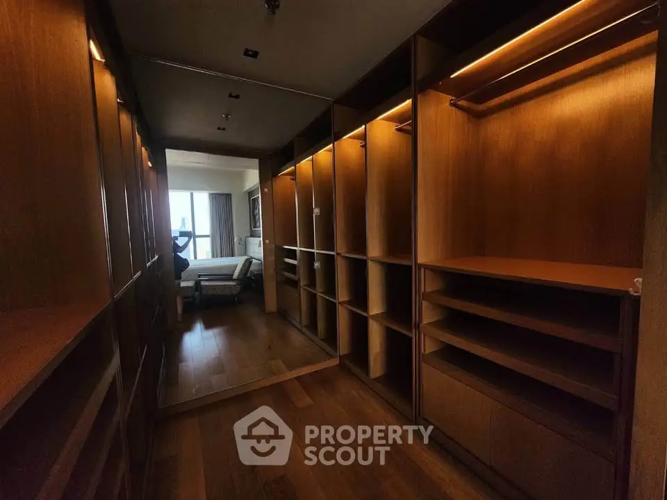 Luxurious walk-in closet with wooden shelves and elegant lighting in a modern apartment.