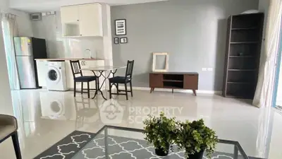Modern open-plan living room with kitchen, featuring sleek furniture and appliances.