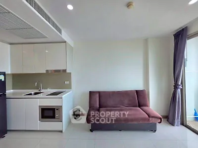 Modern apartment interior with sleek kitchen and cozy living area featuring a stylish sofa.