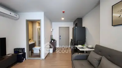 Modern apartment interior with open living area and kitchen, featuring sleek furniture and wooden flooring.
