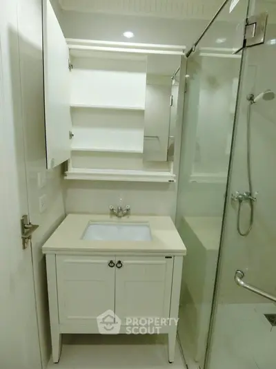 Compact bathroom with modern vanity and glass shower enclosure
