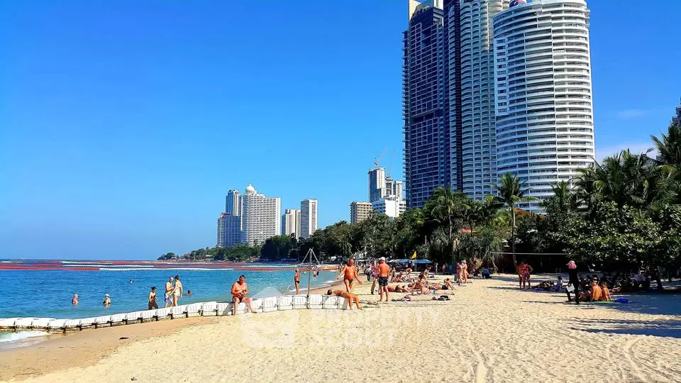 Stunning beachfront view with modern high-rise buildings and vibrant beachgoers enjoying the sunny day.