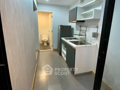 Compact kitchen with modern appliances and adjacent bathroom in a cozy apartment.