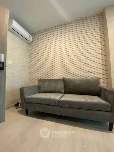 Modern living room with stylish textured wall and comfortable gray sofa, featuring a sleek air conditioning unit.
