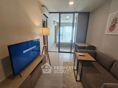 Modern living room with sleek furniture and glass partition leading to bedroom, perfect for urban living.