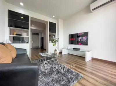 Modern living room with sleek furniture and wall-mounted TV, featuring stylish decor and wooden flooring.