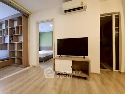 Modern living room with wooden flooring and sleek TV setup in a cozy apartment.