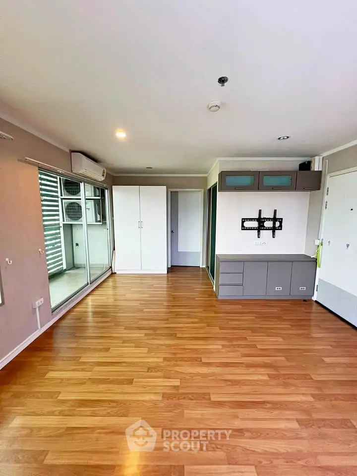 Spacious living room with wooden flooring and modern cabinetry in a bright apartment.