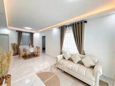 Elegant living room with modern decor and dining area, featuring plush sofa and stylish curtains.
