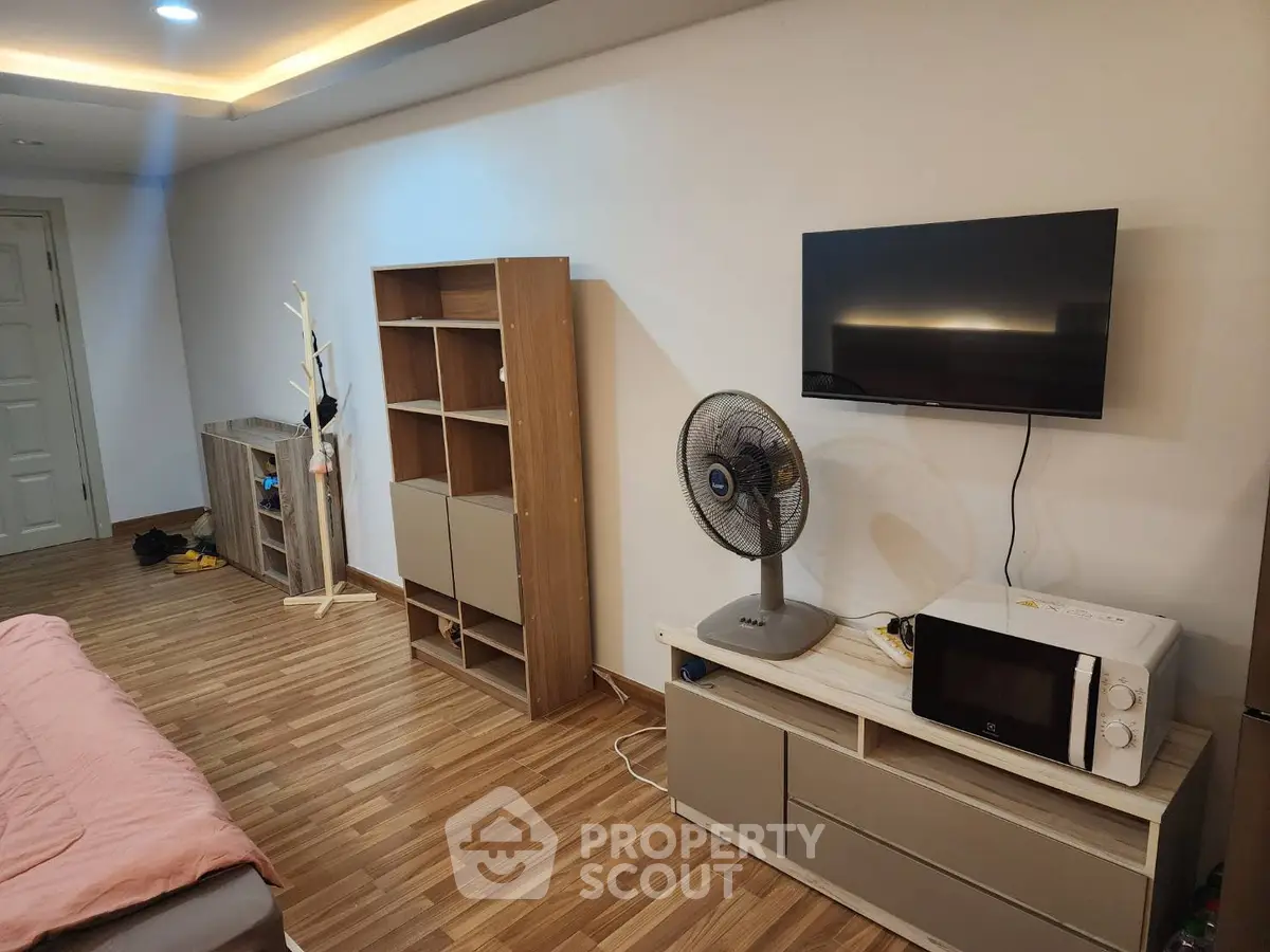 Modern bedroom with wooden flooring, wall-mounted TV, and stylish storage solutions.