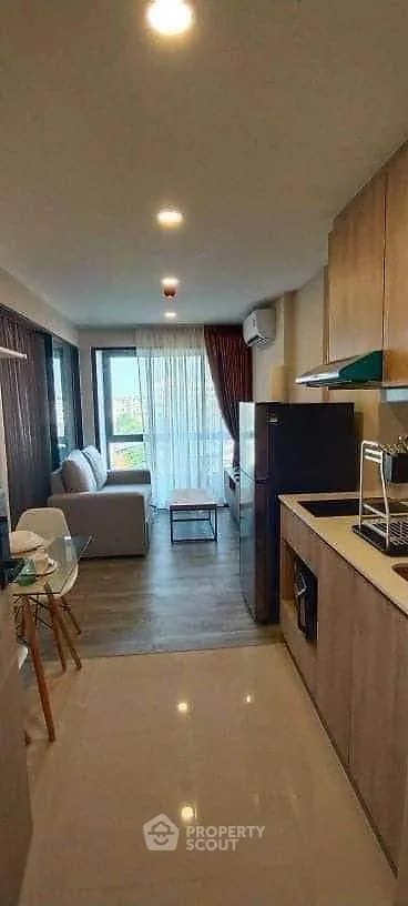 Modern open-layout living room with kitchen, featuring sleek design and natural light.