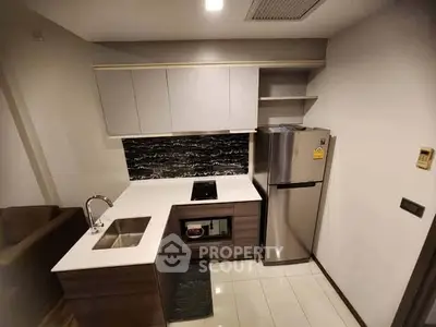 Modern kitchen with sleek cabinetry and stainless steel fridge in compact layout.