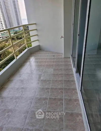 Spacious balcony with tiled flooring and glass doors offering a serene view of the cityscape.