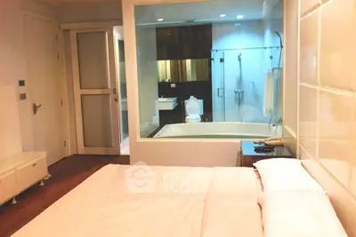 Luxurious bedroom with ensuite bathroom featuring a glass partition and modern amenities.