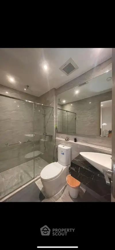 Modern bathroom with glass shower and sleek fixtures in luxury apartment.