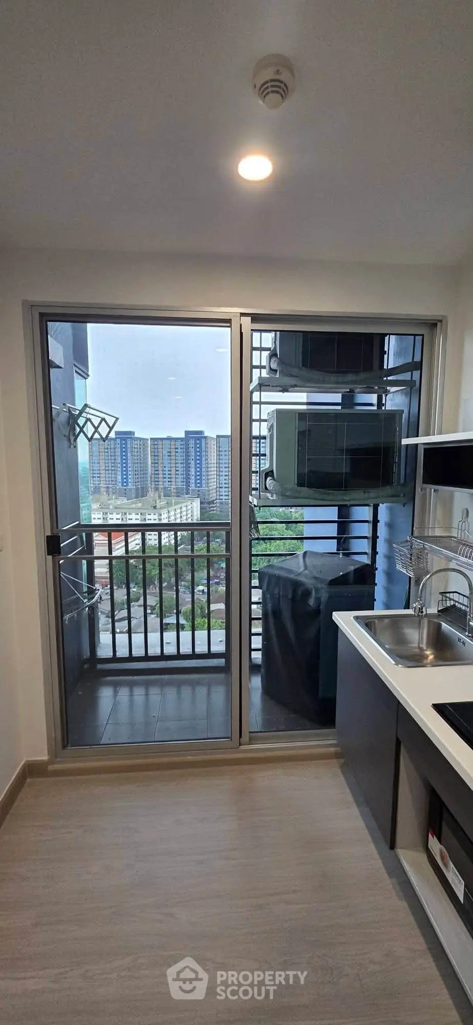 Modern kitchen with balcony view in high-rise apartment, featuring sleek cabinetry and stainless steel appliances.