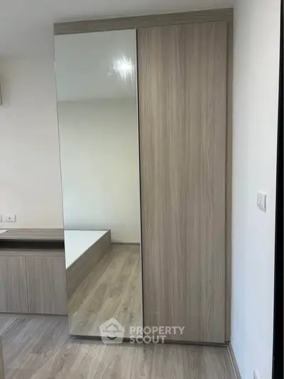 Modern bedroom with sleek mirrored wardrobe and wooden flooring