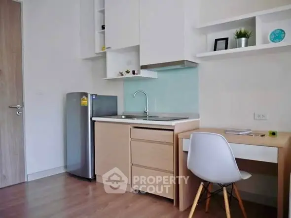 Modern compact kitchen with sleek cabinetry and integrated workspace in a stylish apartment.