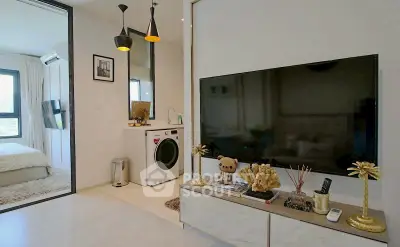 Modern living room with TV and washing machine, adjacent to a cozy bedroom.