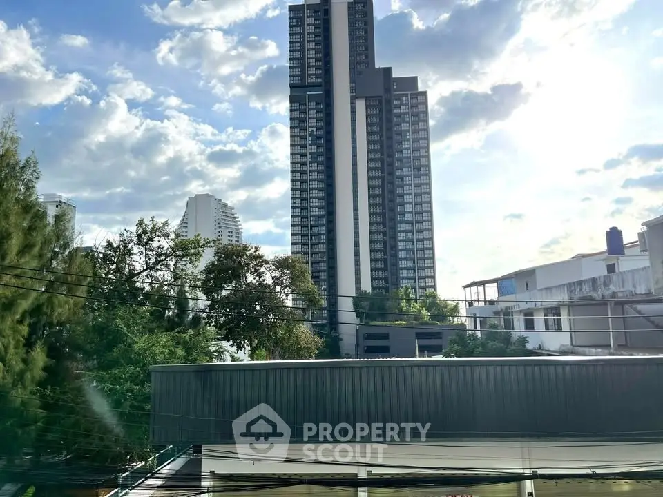 Stunning high-rise building with lush greenery and clear blue sky, perfect urban living.