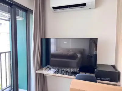 Modern living room with balcony access and wall-mounted TV, featuring sleek air conditioning unit.