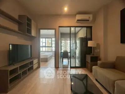 Modern living room with TV, air conditioning, and glass sliding doors leading to bedroom.