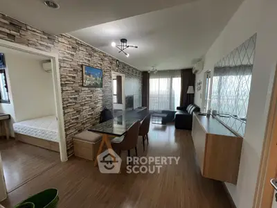 Modern living room with stylish decor and adjacent bedroom, featuring wood flooring and contemporary furniture.