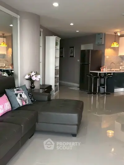 Modern living room with sleek kitchen, featuring stylish decor and open layout for comfortable living.