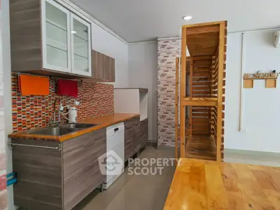 Modern kitchen with sleek cabinetry and colorful backsplash in a stylish apartment.
