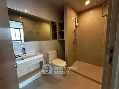 Modern bathroom with sleek fixtures and spacious shower in contemporary apartment.
