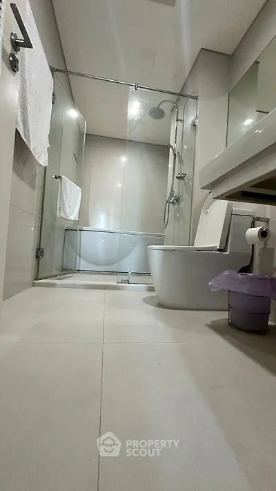 Modern bathroom with glass shower and sleek fixtures in contemporary apartment.